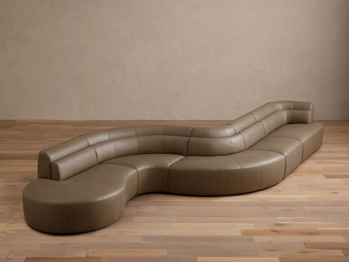Front view of the taupe Lovina Leather Five-Piece Sectional, showcasing its unique serpentine curved design.