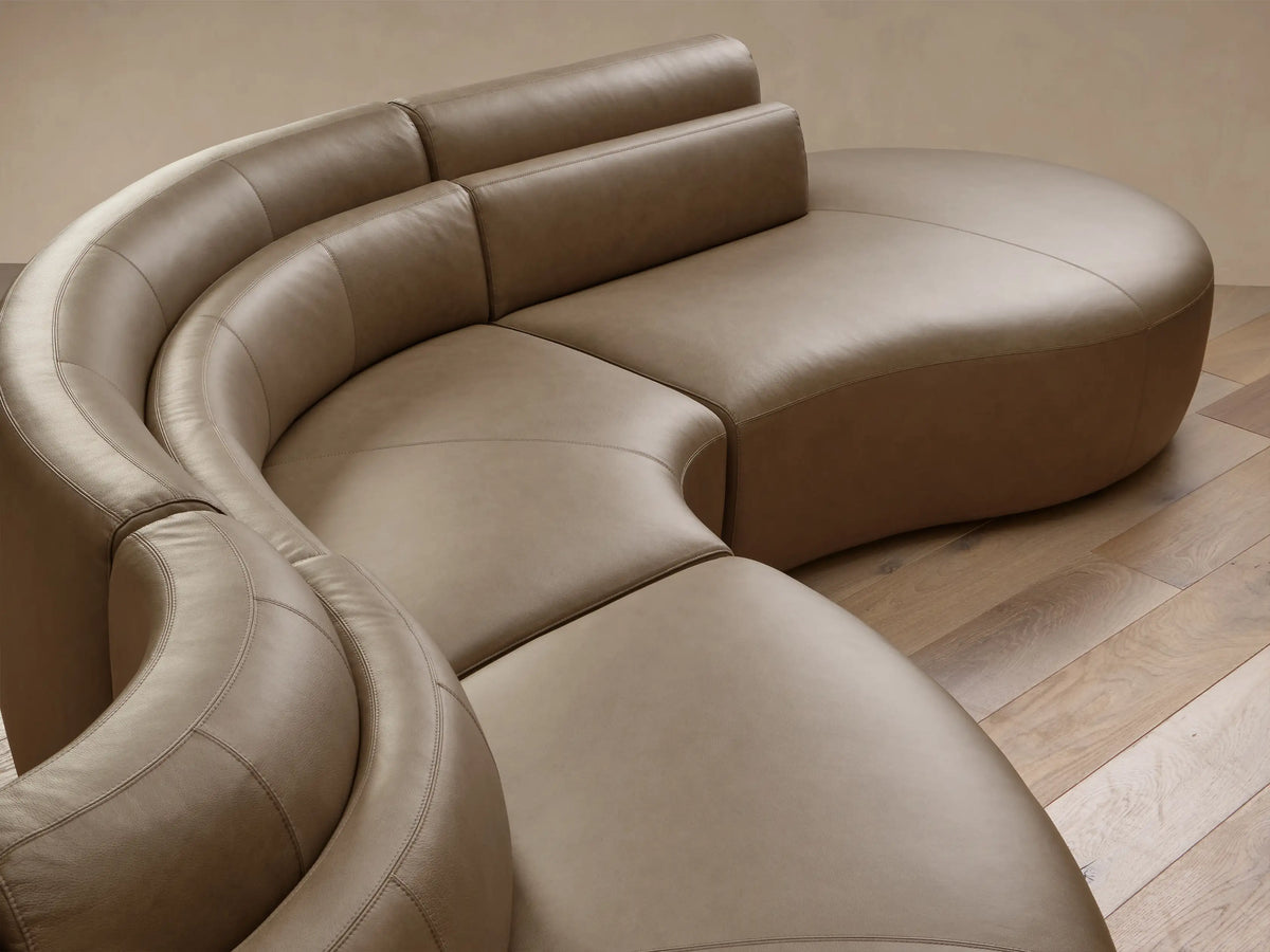 Full view of the taupe Lovina Leather Five-Piece Sectional with a curved, serpentine design and segmented backrests.
