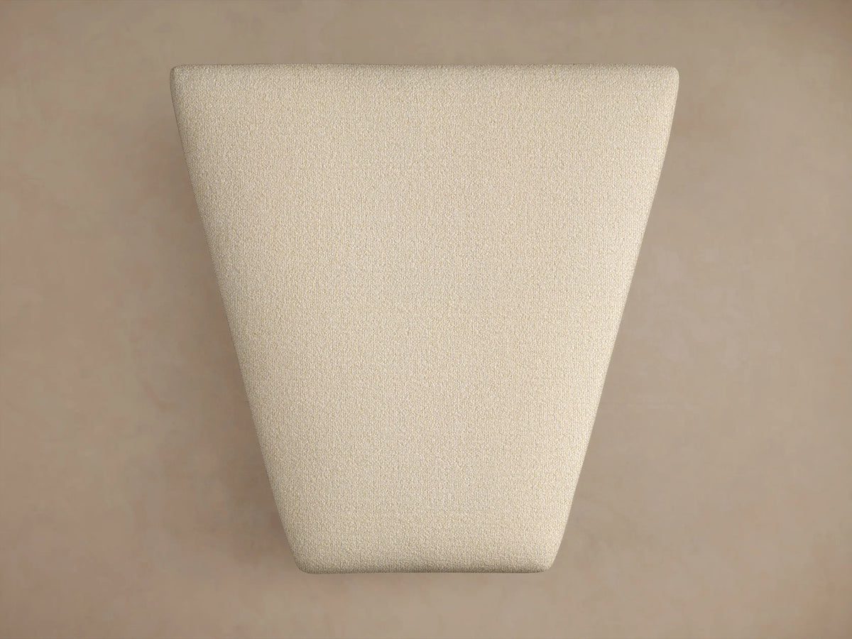 Lovina Ottoman in light beige textured fabric, rectangular with soft rounded corners, small dark feet, on a warm beige background.