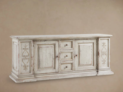 Vittoria Bell'Arte Console with hand-carved ivory grey and dark rust finish, ornate door detailing, brass knobs, and wood grain texture.