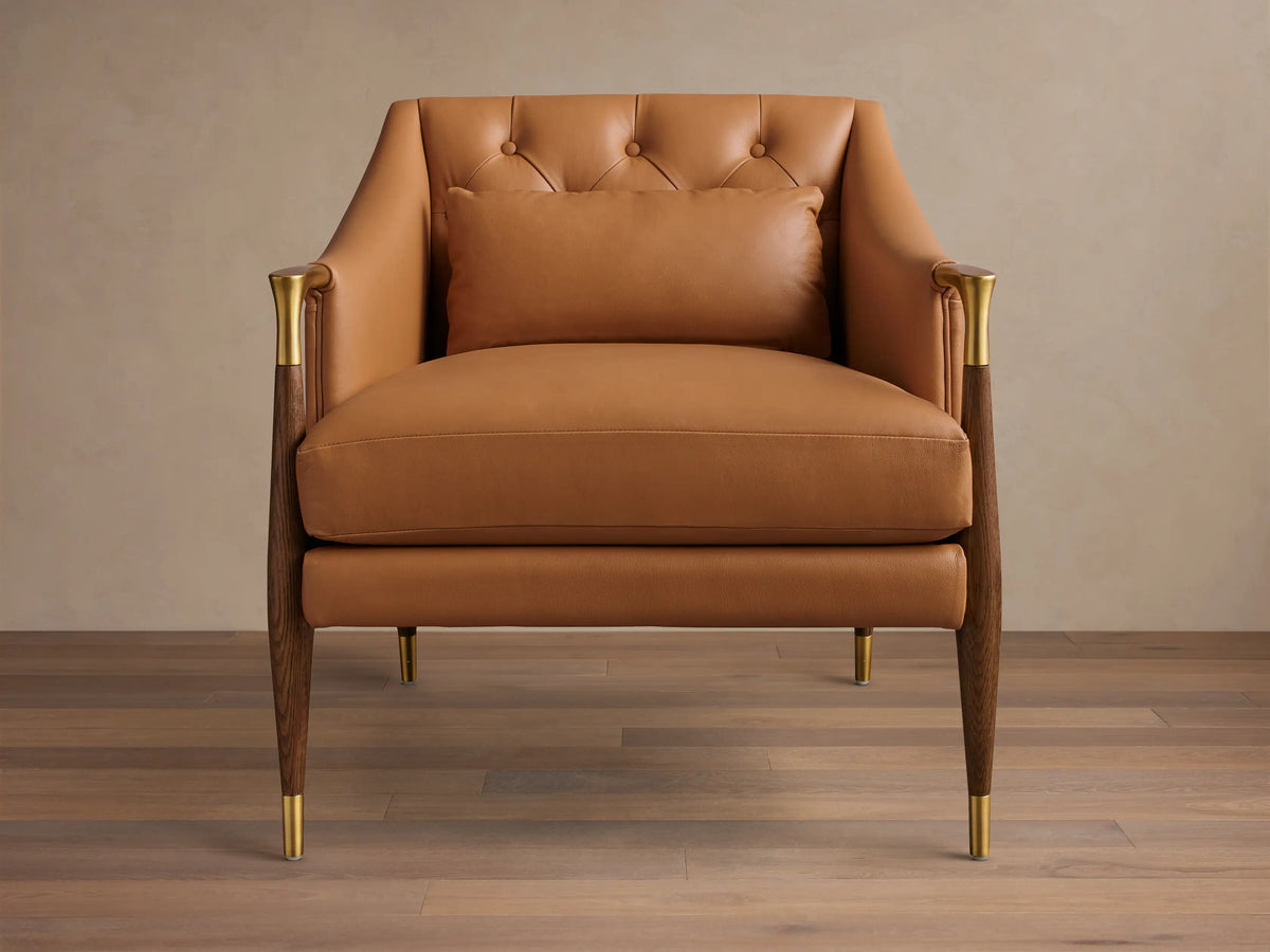 Front view of a Cognac Fisher Leather Club Chair with a button-tufted back, wood and brass armrests, tapered legs, and lumbar pillow.