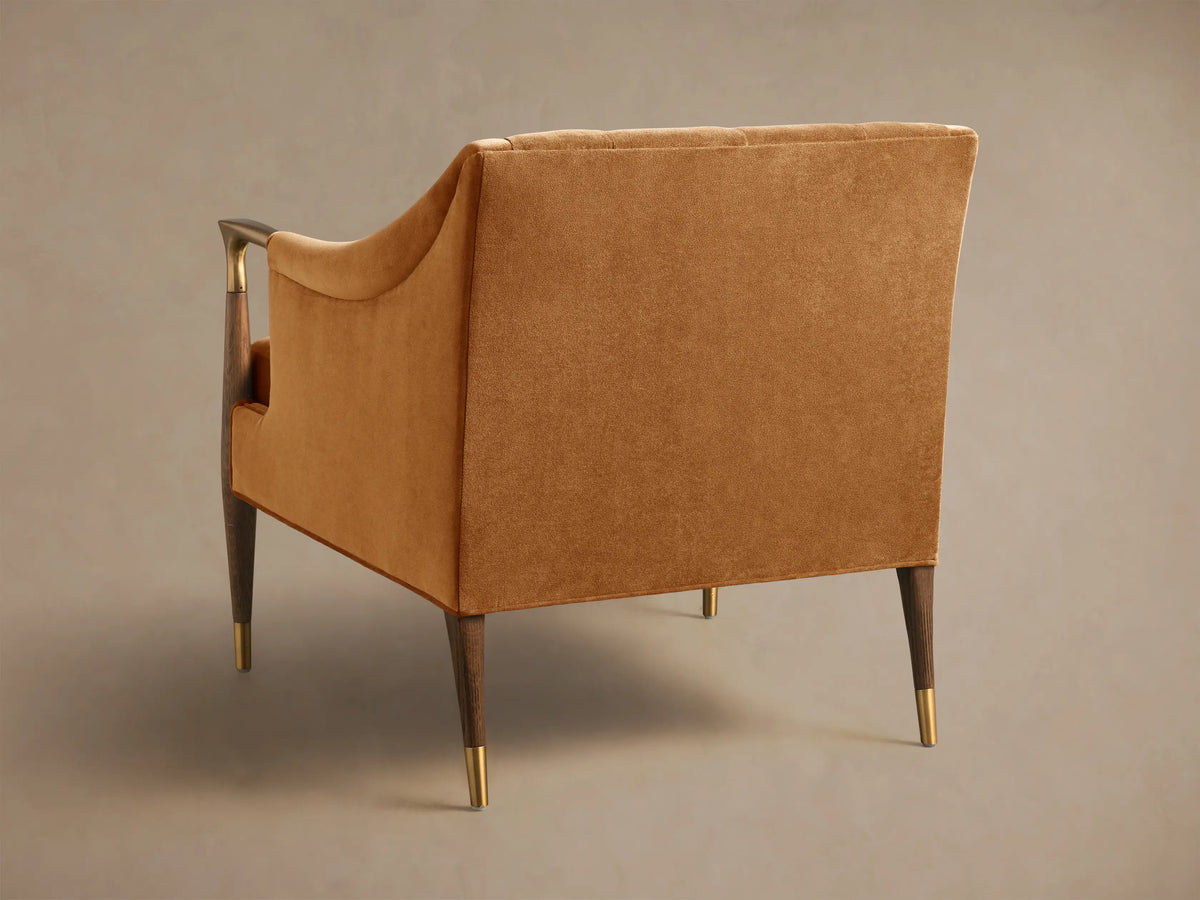 Front view of the cognac brown velvet Fisher Club Chair with tufted back, lumbar pillow, and brass-capped wooden legs.