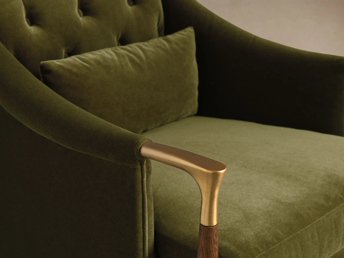 Front view of the olive green velvet Fisher Club Chair with a tufted back, wooden arms, brass accents, and a matching lumbar pillow.