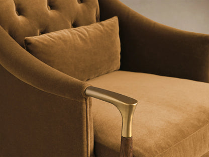 Front view of the Golden brown velvet Fisher Club Chair with tufted back, wood and brass armrests, tapered legs, and lumbar pillow.