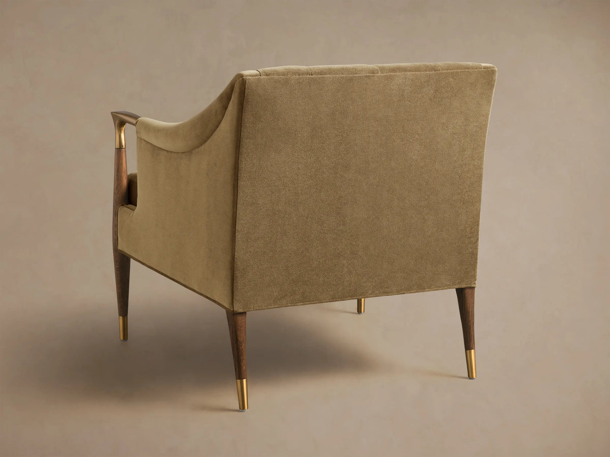 Rear-side view of a moss green Fisher Club Chair, featuring dark wood legs with brass caps and wood and brass arm details.