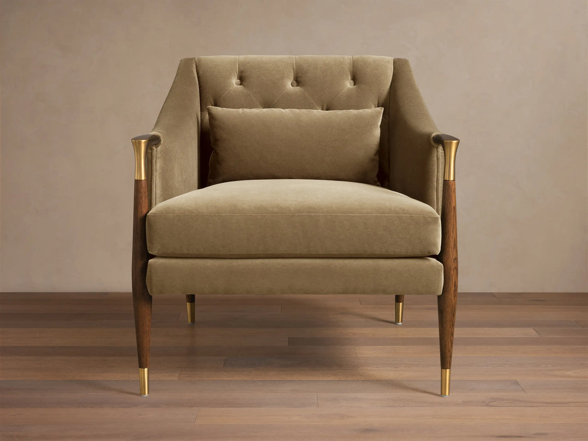 Front view of the khaki velvet Fisher Club Chair with tufted back, lumbar pillow, wooden arms with brass accents, and brass-capped legs.