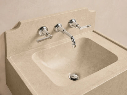 Angled view of a beige honed stone Dottie Wall-Mounted Sink with Backsplash, with three faucet holes and a curved top edge.