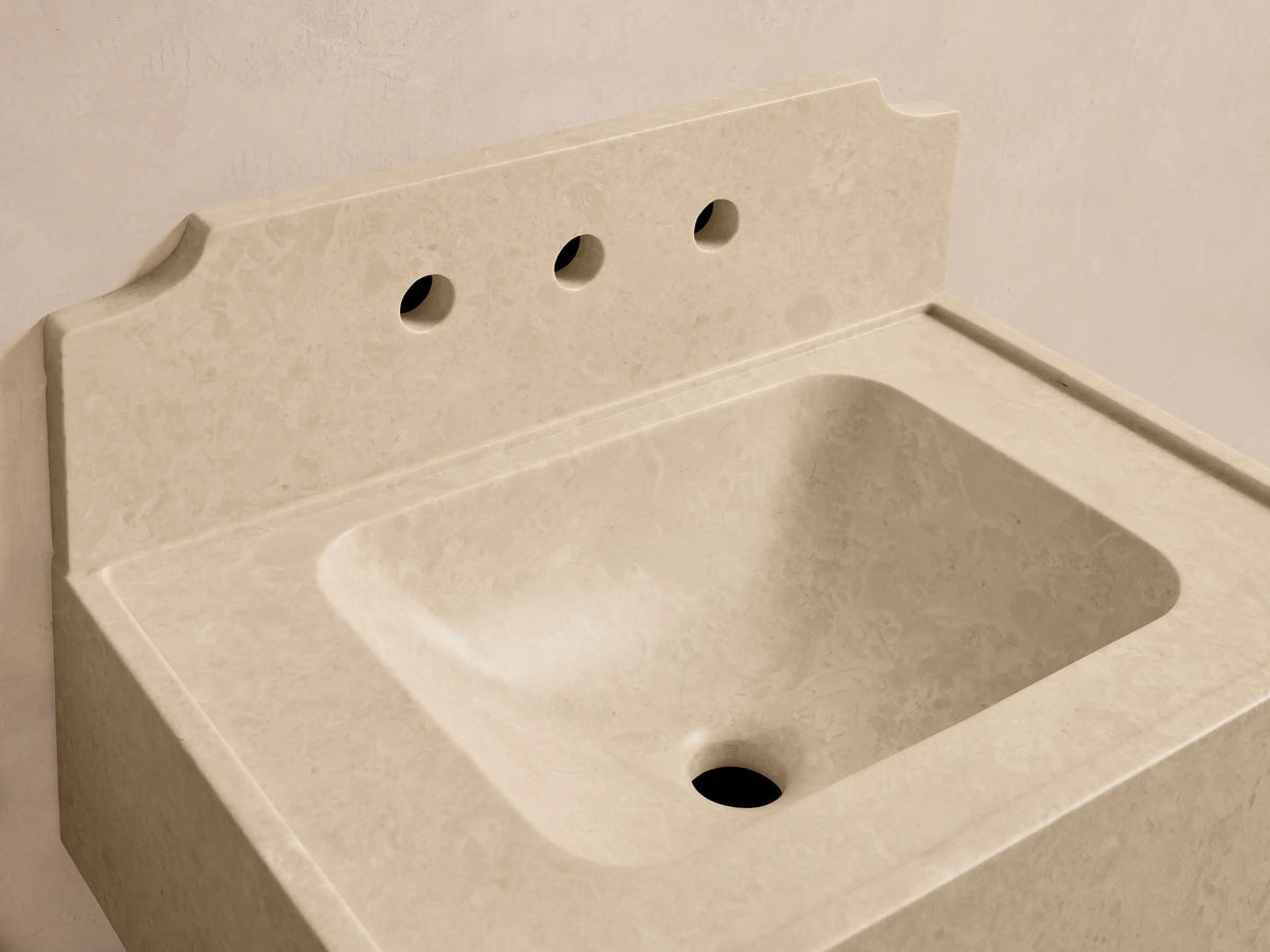 Front view of the cream Dottie Wall-Mounted Sink with Backsplash, made of honed stone with a built-in basin and chrome faucet.