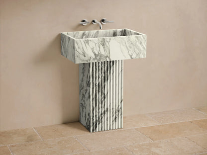 Front view of the white and gray veined Riven Pedestal Sink, featuring a fluted base and rectangular basin.