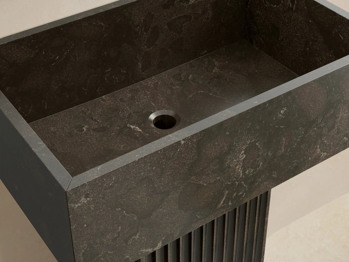 Front view of the dark gray Riven Pedestal Sink with a rectangular basin and fluted base, showing natural stone texture.