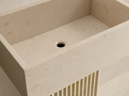 Front view of the light beige honed stone Riven Pedestal Sink with a rectangular basin and fluted pedestal base.