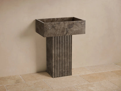 Front view of the dark grey Riven Pedestal Sink, featuring a rectangular basin with marble-like veining and a fluted pedestal base.