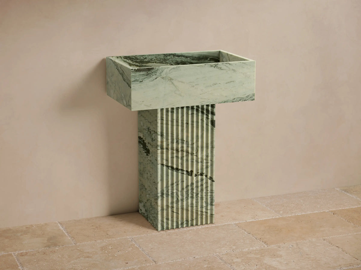 Front view of green marbled Riven Pedestal Sink, showcasing fluted base and natural black veining.