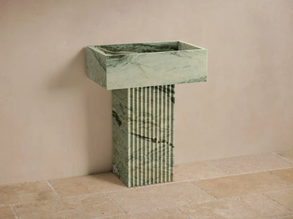 Front view of green marbled Riven Pedestal Sink, showcasing fluted base and natural black veining.