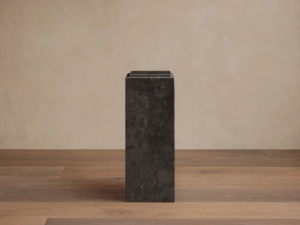 Front view of a dark gray Marmont Pedestal made of honed stone, showing natural veining and a stepped top design.