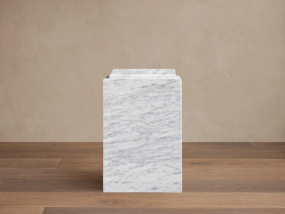 Front view of a white Marmont Pedestal, made of marble with grey veining and a stepped top design.