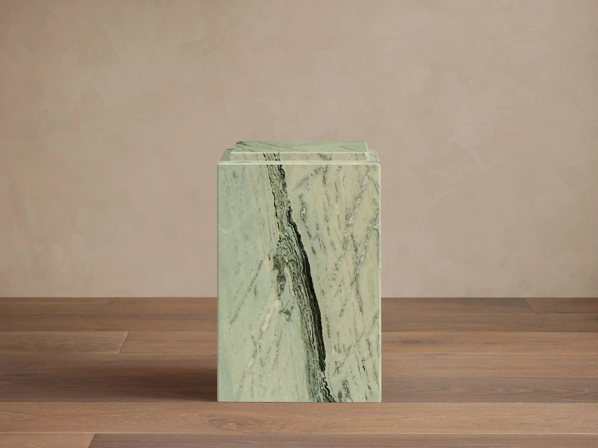 Front view of a light green Marmont Pedestal with prominent dark green and black marble veining, standing on a wooden floor.