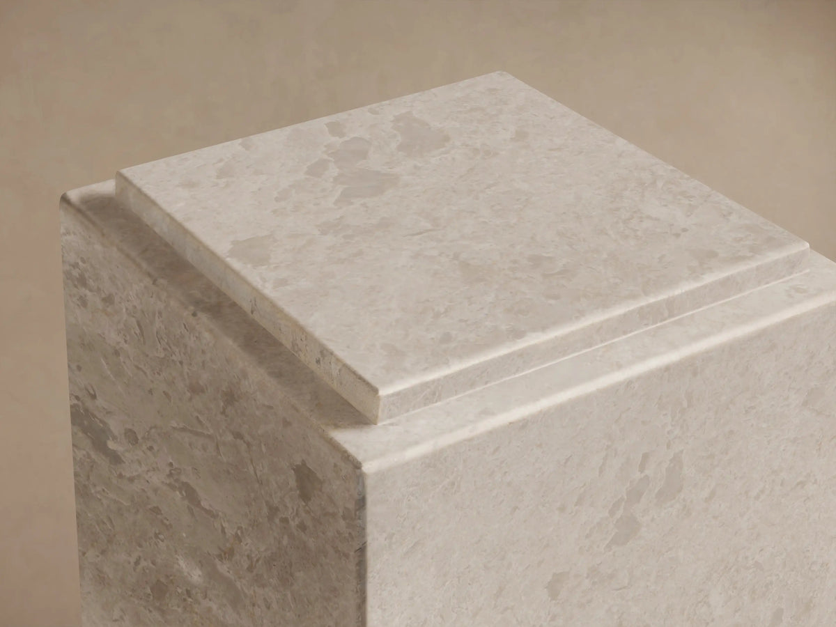 Close-up of the light gray natural stone Marmont Pedestal with visible veining and a distinctive stepped top design.