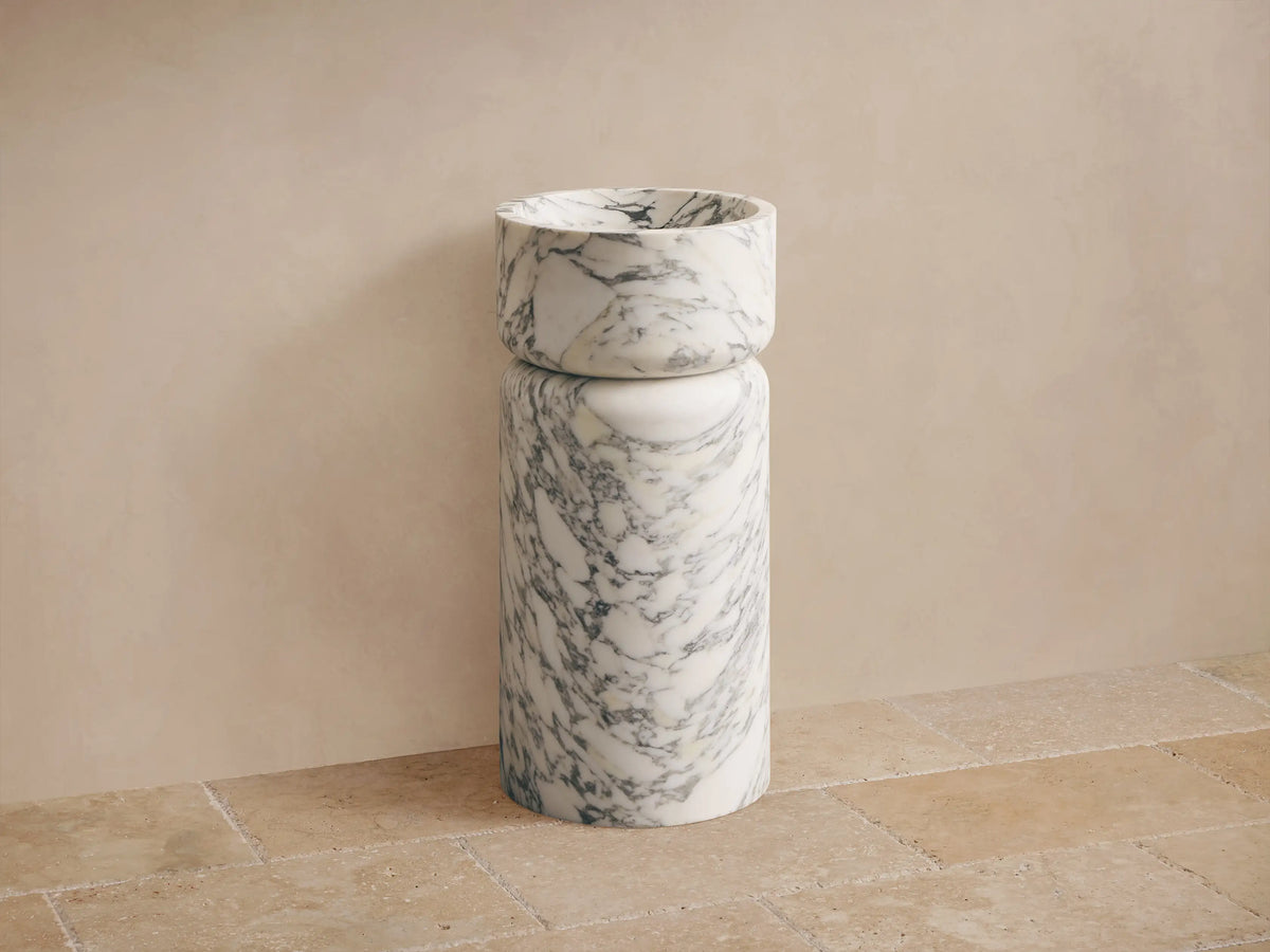Close-up of white marble container, with natural gray veining and a smooth, curved rim.