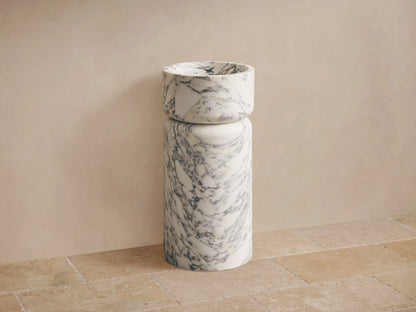 Close-up of white marble container, with natural gray veining and a smooth, curved rim.