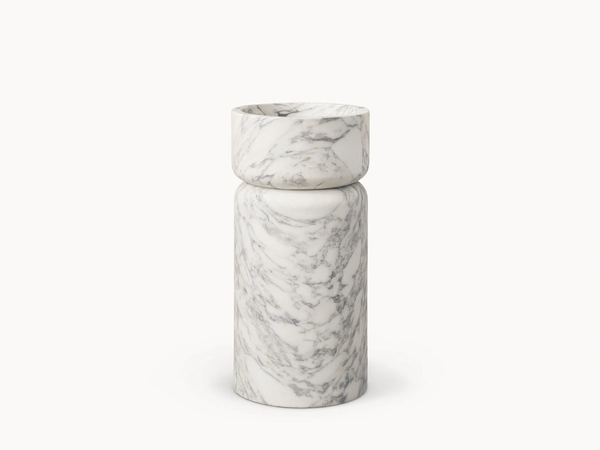 Front view of a white marble pedestal sink with prominent grey veining, featuring a rounded basin atop a cylindrical base.