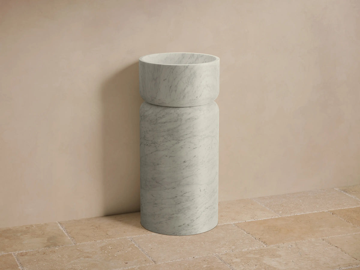 Front view of the grey-veined white marble Vaso Pedestal Sink, featuring a cylindrical base and integrated round basin.