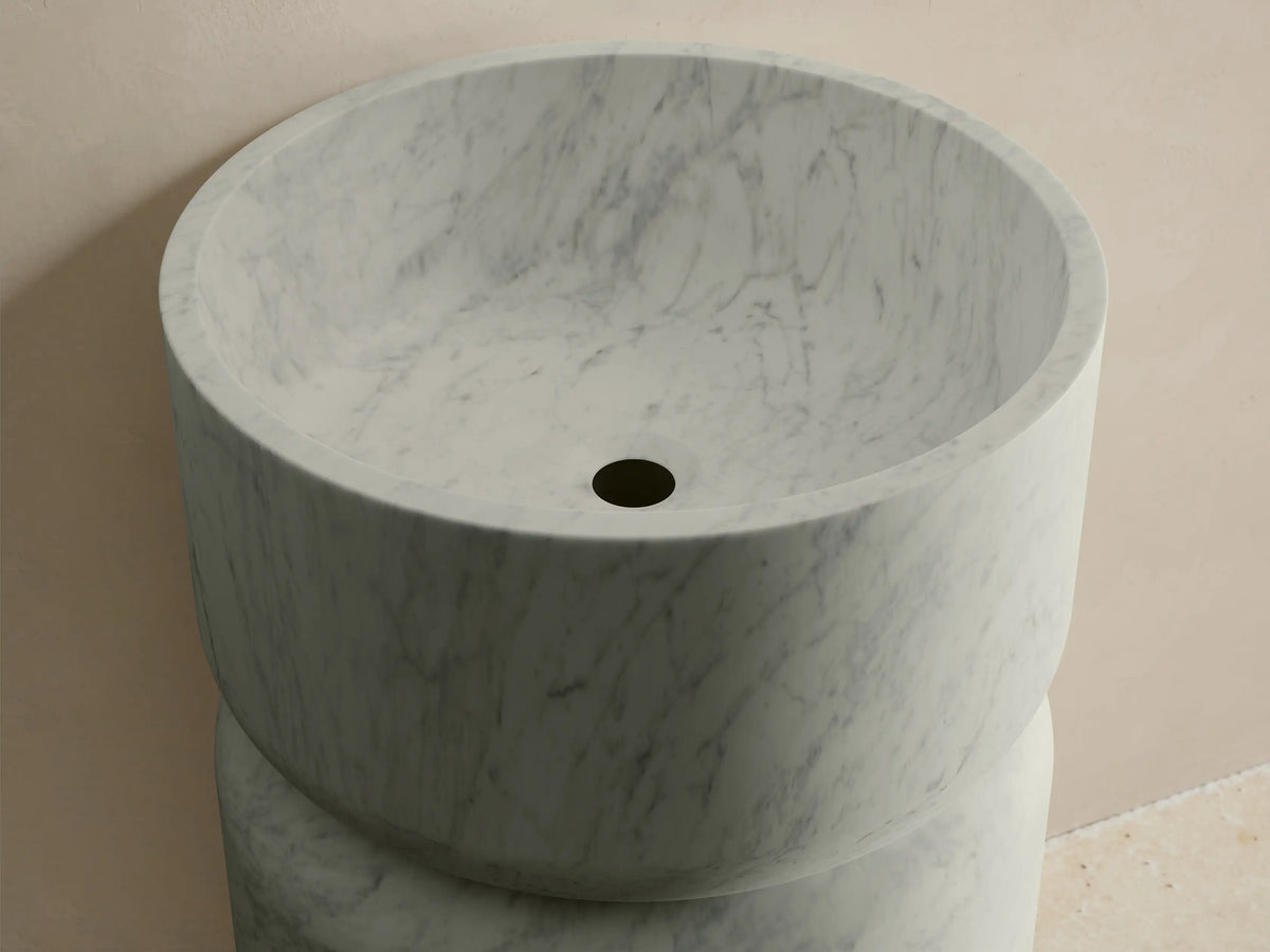 Front view of the light grey marble Vaso Pedestal Sink, featuring a cylindrical base and a wider integrated basin.