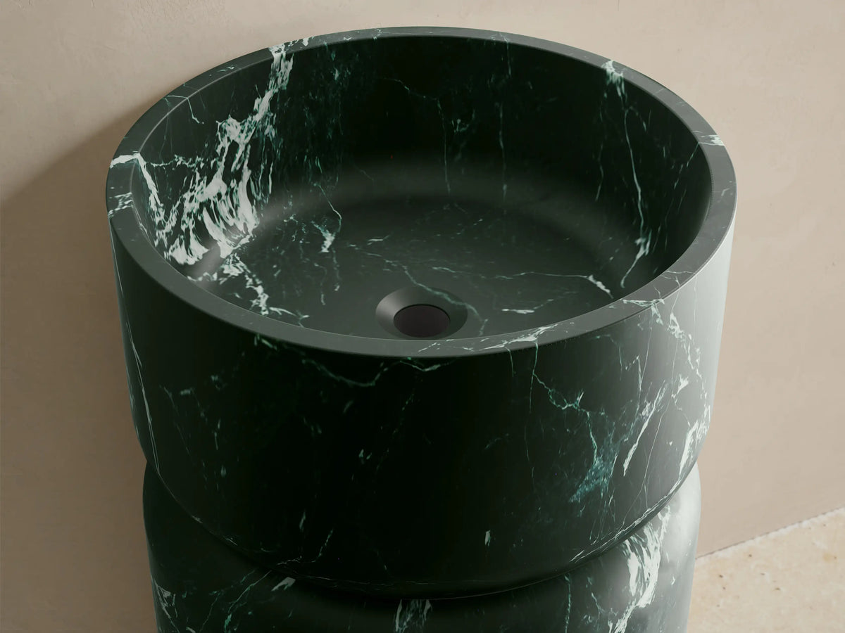 Front view of the dark green marble Vaso Pedestal Sink with white veining, featuring a cylindrical shape and integrated basin.