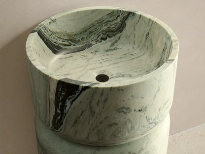 Front view of the green marble Vaso Pedestal Sink, featuring a cylindrical base, integrated bowl top, and natural veining.