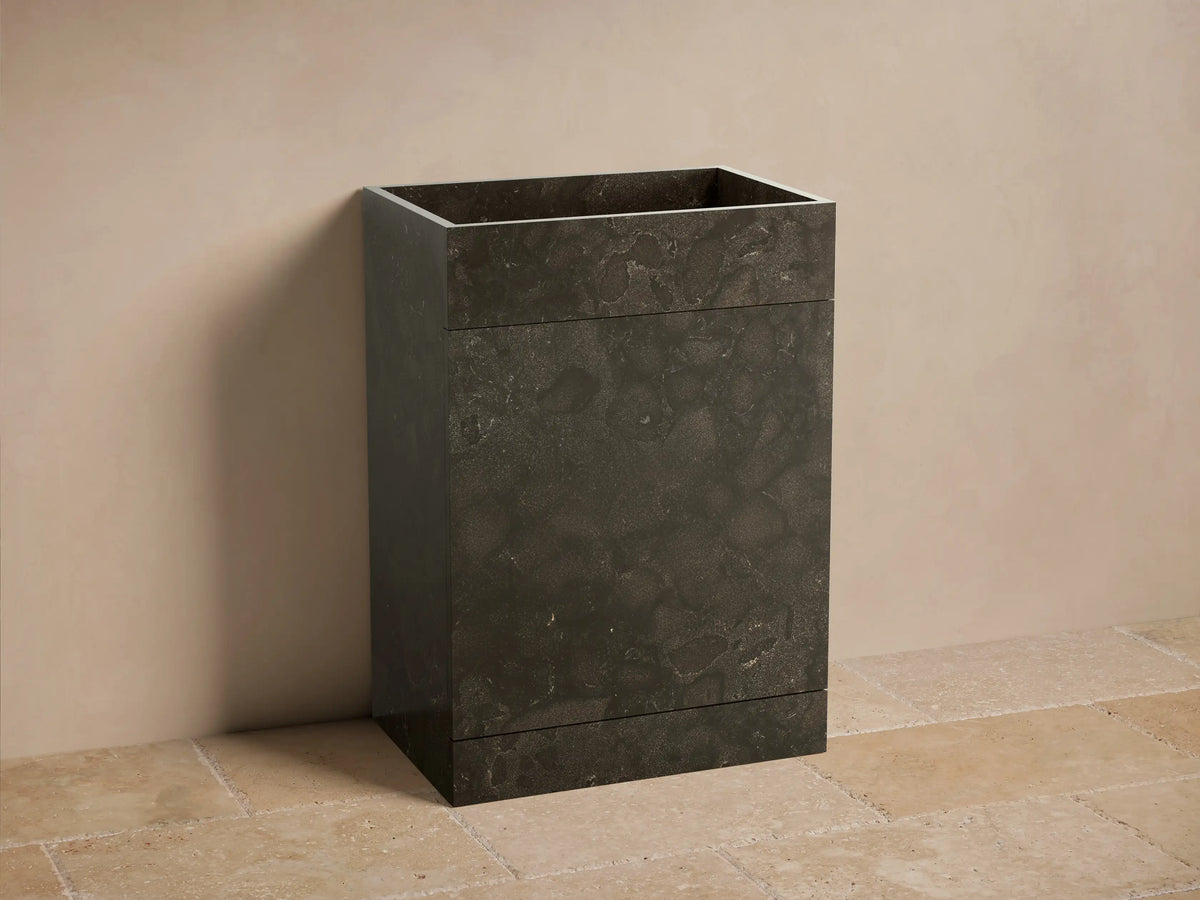 Front view of the dark grey honed stone Vertiz Pedestal Sink with Storage, featuring visible natural variations in the stone.