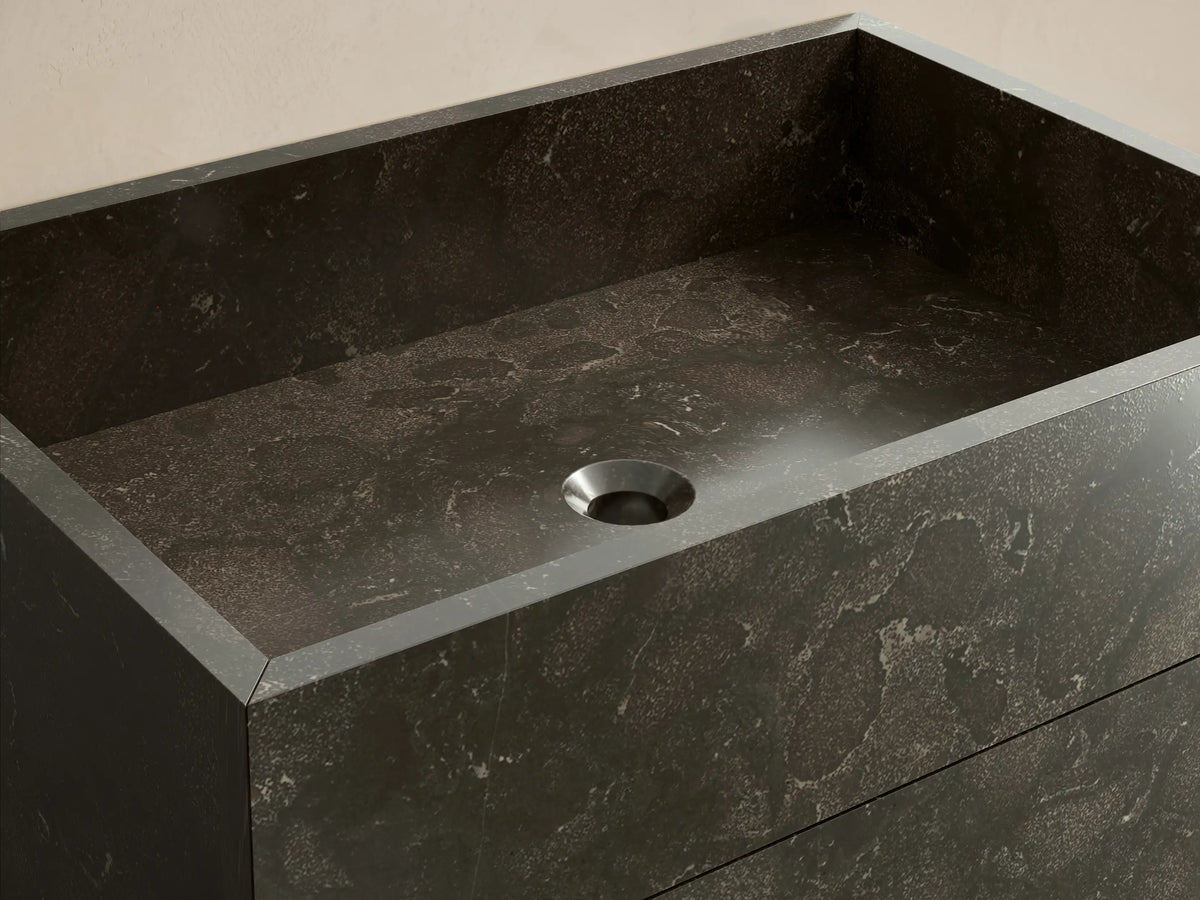 Front view of the dark mottled honed stone Vertiz Pedestal Sink with Storage, showcasing natural variations.