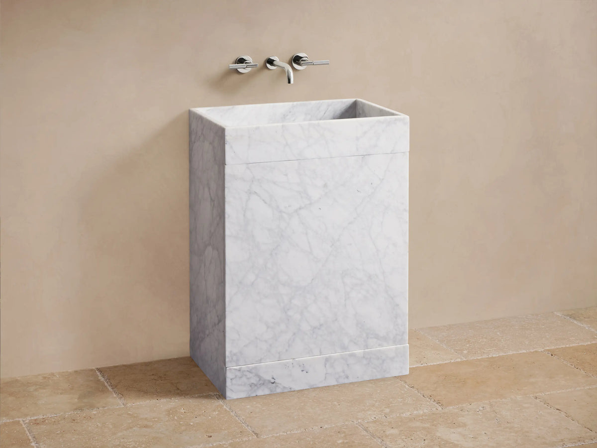 Front view of a white marble vanity with integrated sink. Left door open, revealing a woven basket of rolled towels.