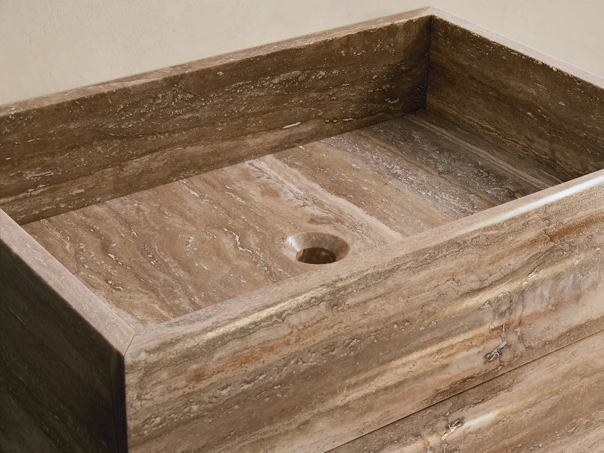 Front view of the Vertiz Pedestal Sink with Storage, featuring a light and dark brown natural stone exterior with horizontal veining.