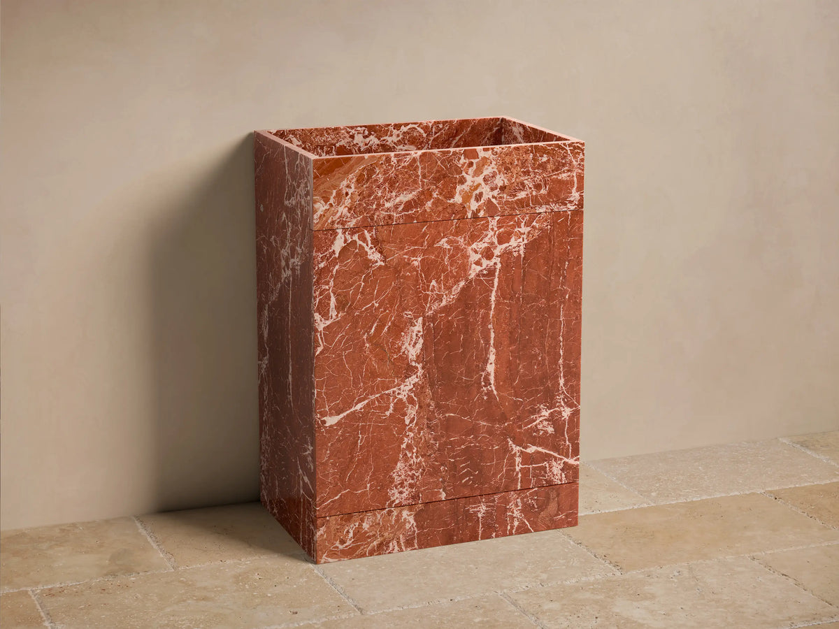 Front view of the Vertiz Pedestal Sink with Storage, made from red marble with white veining, featuring a rectangular basin.