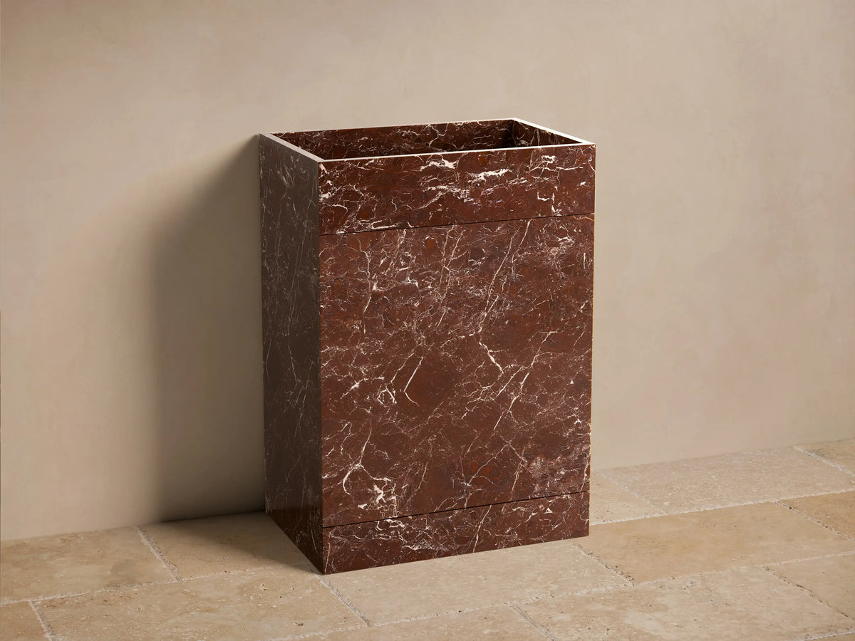 Front view of a reddish-brown marbled Vertiz Pedestal Sink with Storage, made of honed stone with white veining.