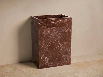Front view of a reddish-brown marbled Vertiz Pedestal Sink with Storage, made of honed stone with white veining.