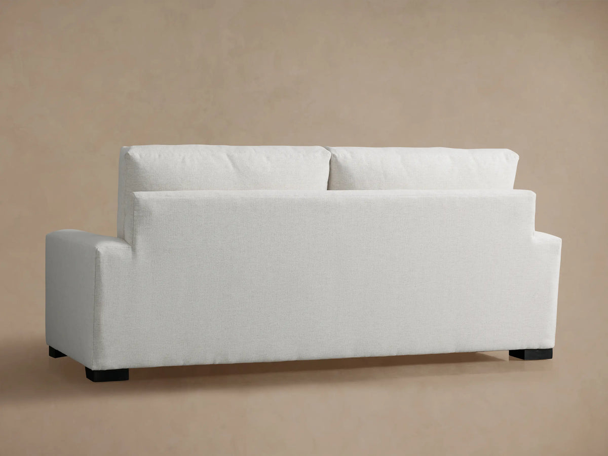 Close-up of a Remington Sofa, showing the light cream textured fabric on its plush back cushion, seat, and armrest.