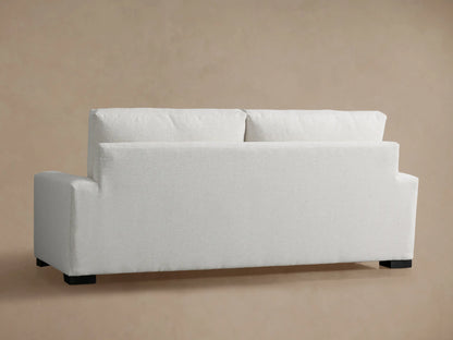 Close-up of a Remington Sofa, showing the light cream textured fabric on its plush back cushion, seat, and armrest.