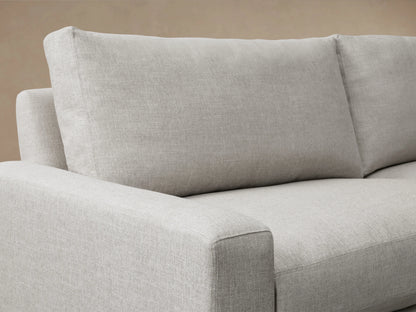 Close-up of a light gray Remington Sofa, showing a square armrest, two plush back cushions, and textured fabric.