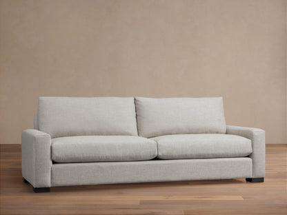 Front view of a light gray Remington Sofa with two seat cushions, two back cushions, and wide arms, on a wooden floor.