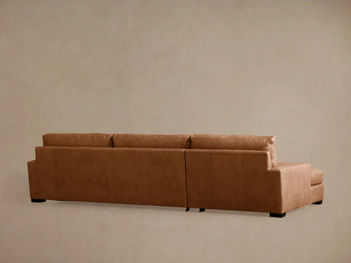 Close-up of Remington leather sectional in rich brown. Shows back cushion, seat, and armrest with visible stitching details.
