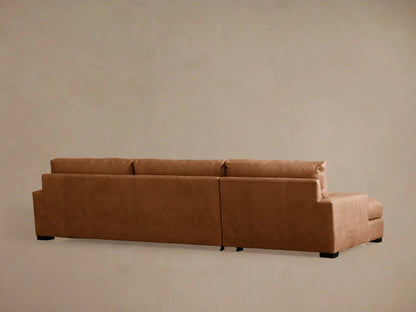 Close-up of Remington leather sectional in rich brown. Shows back cushion, seat, and armrest with visible stitching details.