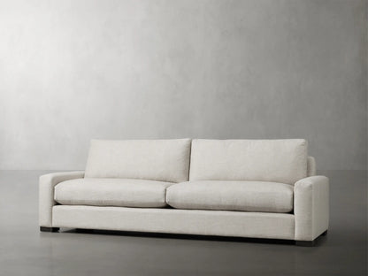 Remington Sofa, upholstered in light cream fabric with two back cushions, two seat cushions, and low square arms.