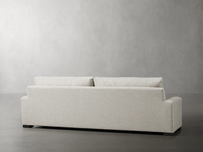 Close-up of Remington Sofa's back cushion and armrest in light beige/grey textured fabric with visible seams.