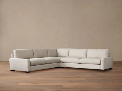 Off-white Remington Three-Piece Corner Sectional, an L-shaped sofa with plush cushions, against a warm beige wall & wood floor.