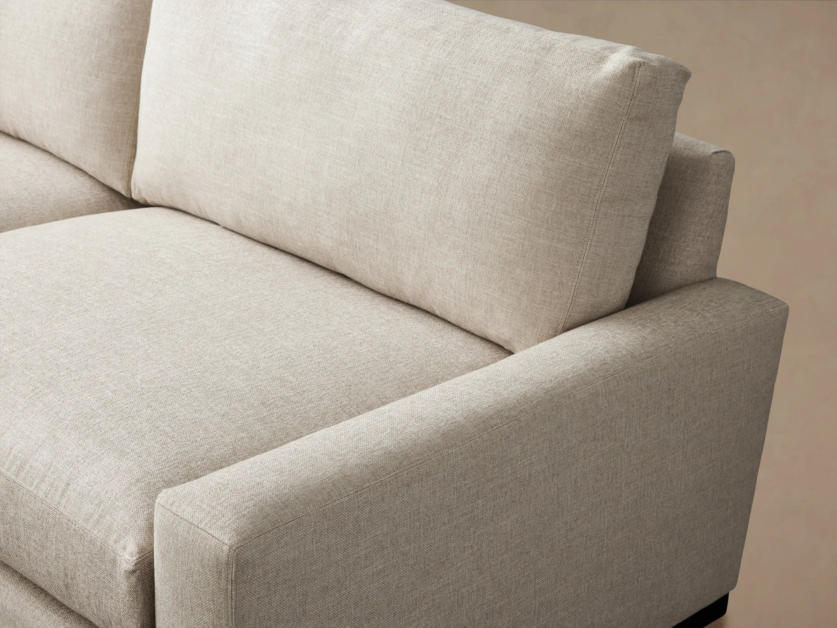 Light beige, L-shaped Remington Three-Piece Corner Sectional with plump cushions & wide arms, on a wooden floor.