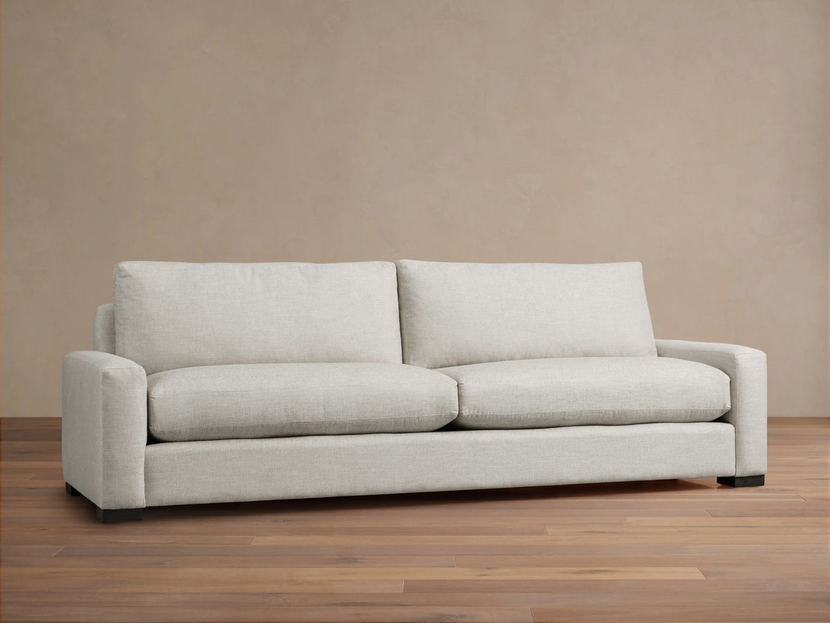 Rear view of a Remington Sofa in light gray textured fabric. Features two back cushions, square arms, and dark block feet.