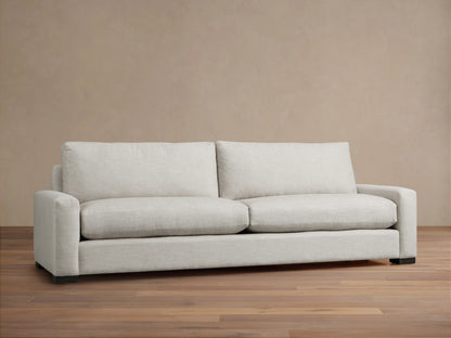 Rear view of a Remington Sofa in light gray textured fabric. Features two back cushions, square arms, and dark block feet.