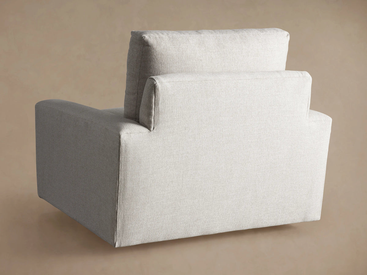 Close-up of the light beige textured fabric on the seat, back cushion, and armrest of a Remington Swivel Chair.