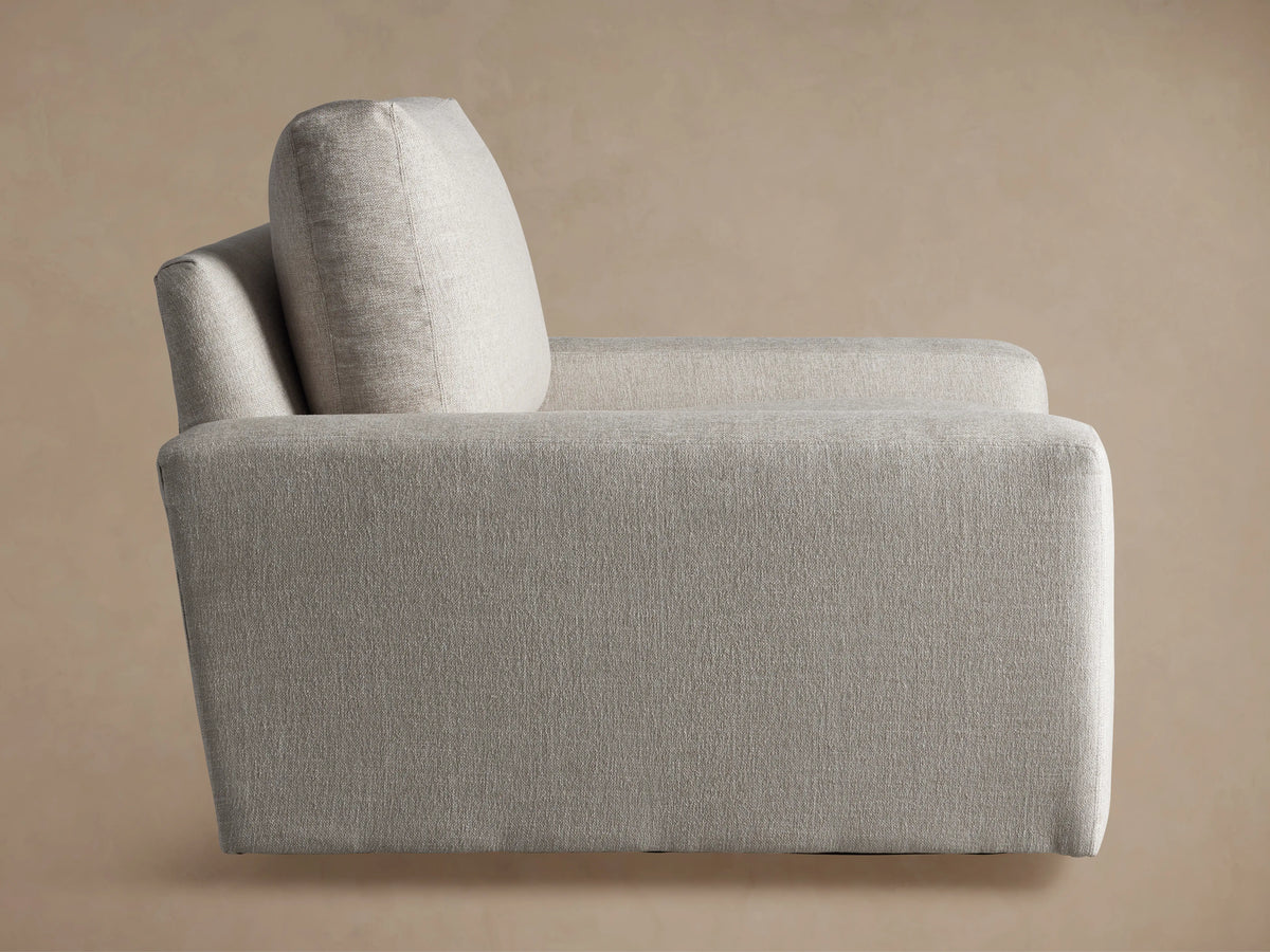 Rear view of the light grey textured Remington Swivel Chair, highlighting its blocky design and armrest.